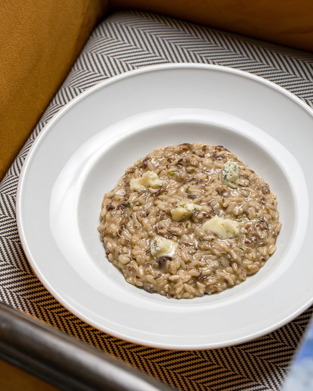 Risotto crémeux aux morceaux de fromage bleu dans une assiette creuse blanche