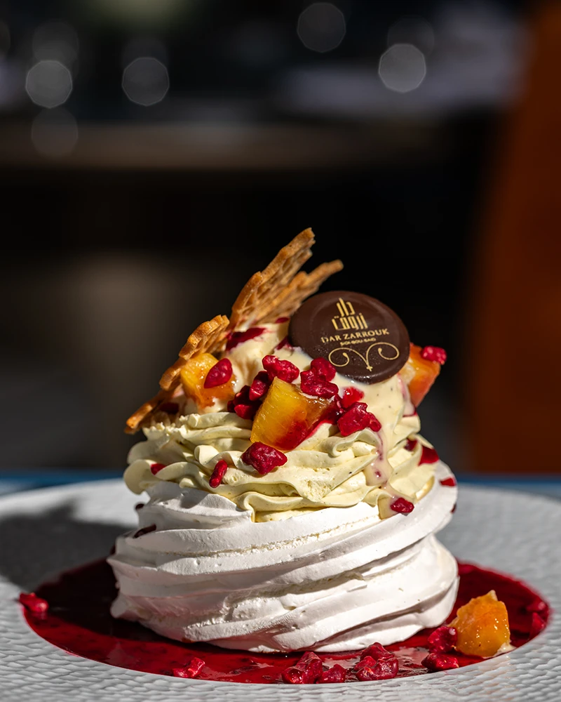 Pavlova meringuée à la crème, fruits rouges et croustillant, avec médaillon en chocolat Dar Zarrouk