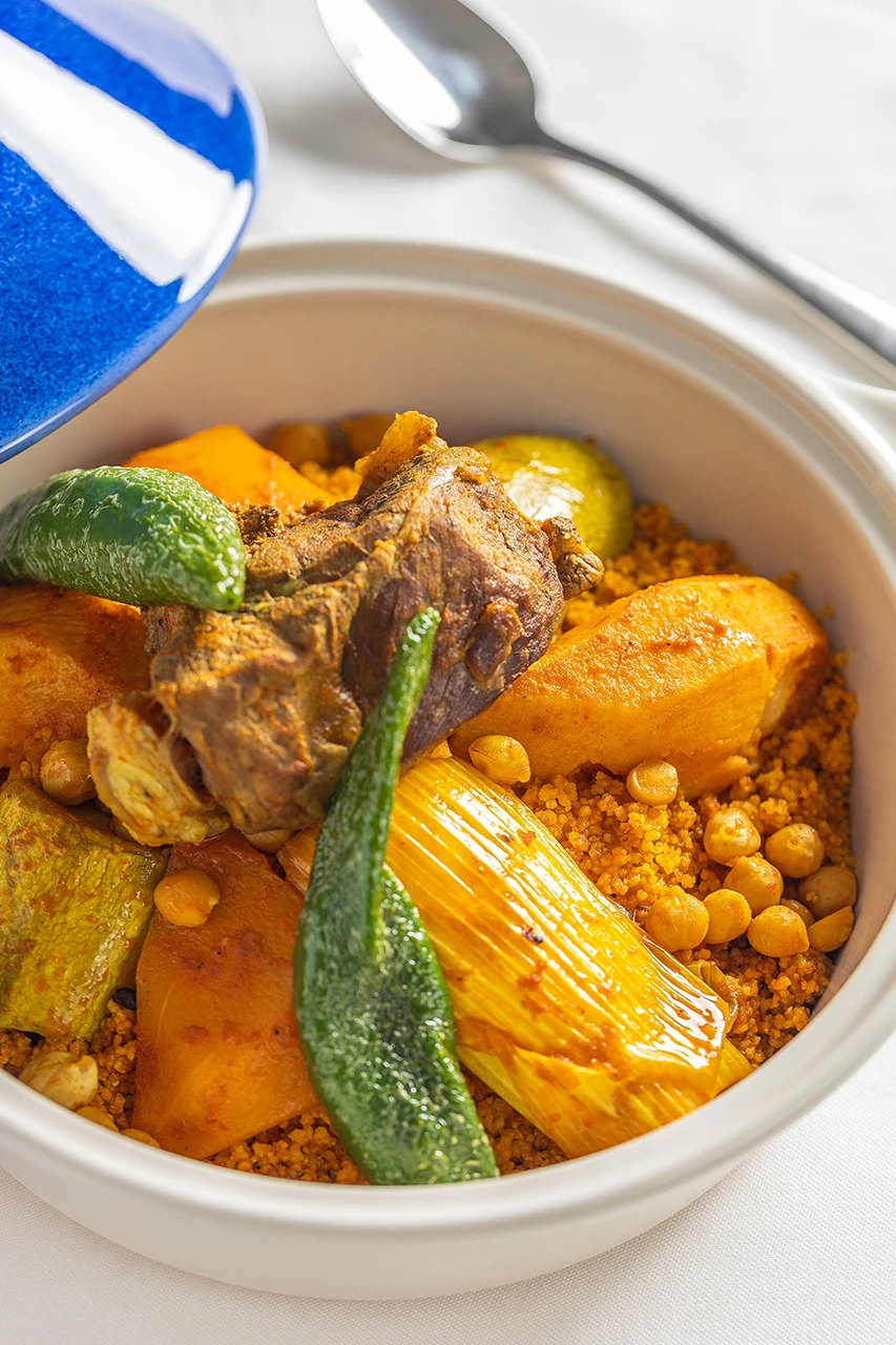 Couscous tunisien à l’agneau, légumes et pois chiches servi dans un plat en terre blanc