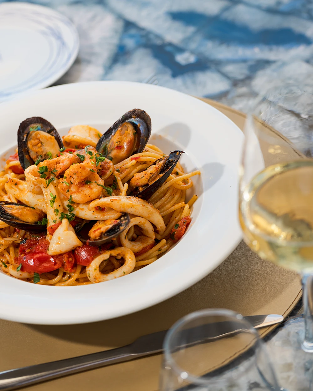 Spaghettis aux fruits de mer, moules, gambas et calamars, avec un verre de vin blanc