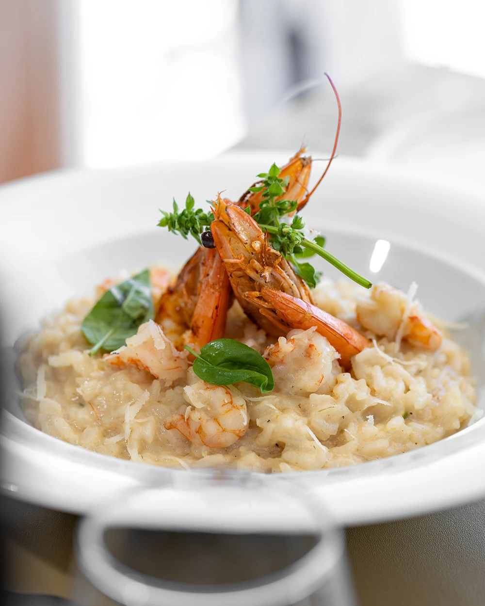 Risotto crémeux garni de grosses crevettes grillées et de feuilles de basilic